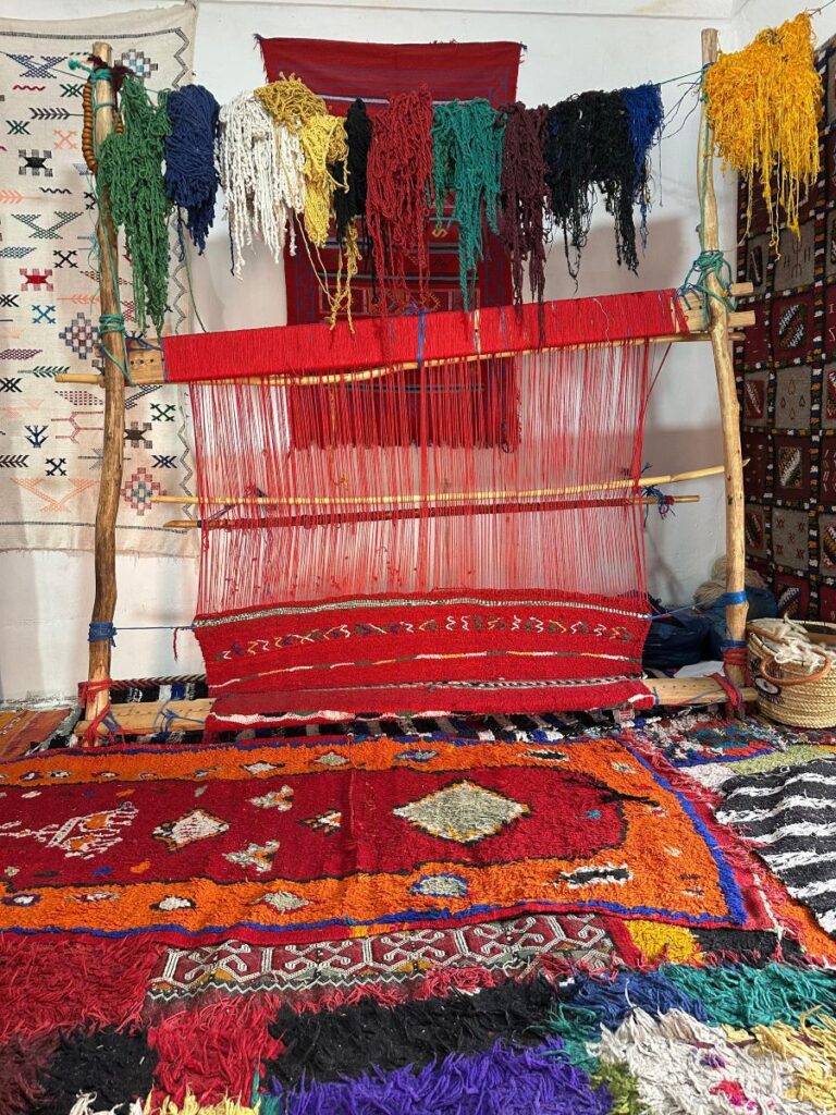 Berber artisan woman hand-knotting authentic Moroccan rug on vertical loom showing traditional weaving technique knot by knot