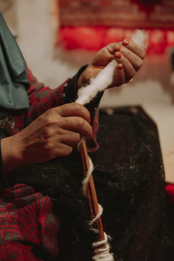 Berber artisan woman hand-knotting authentic Moroccan rug on vertical loom showing traditional weaving technique knot by knot
