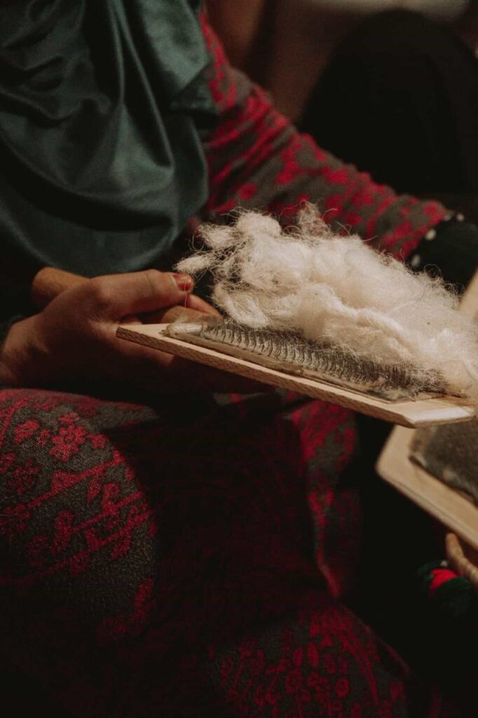 Berber artisan hand-spinning natural sheep wool using traditional drop spindle for authentic Moroccan rug weaving
