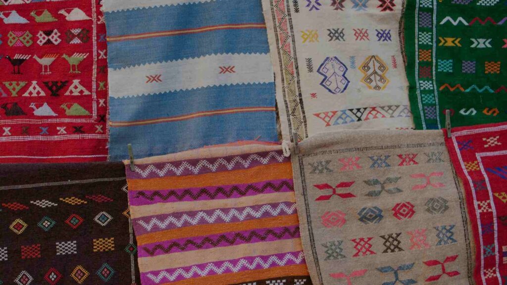 Close-up detail of traditional Moroccan Berber rug symbolic patterns including diamonds, zigzags and protective eye motifs in natural wool
